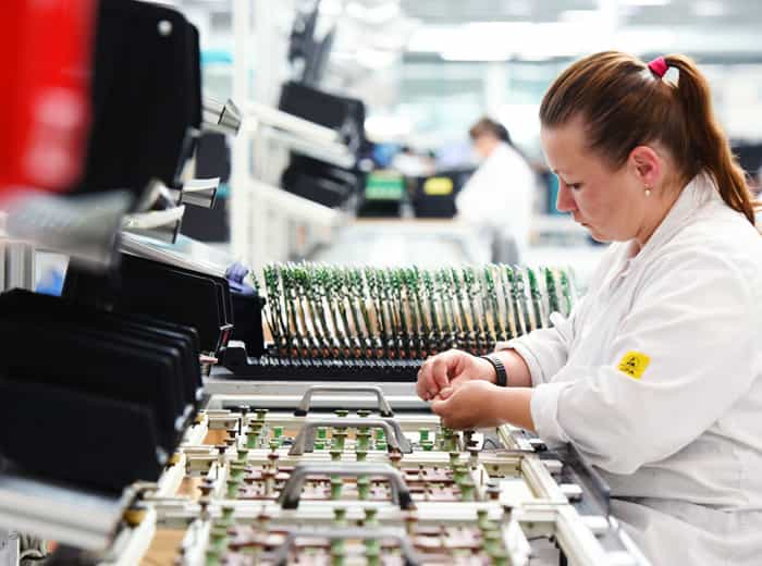 A worker is performing a through-hole PCB assembly job