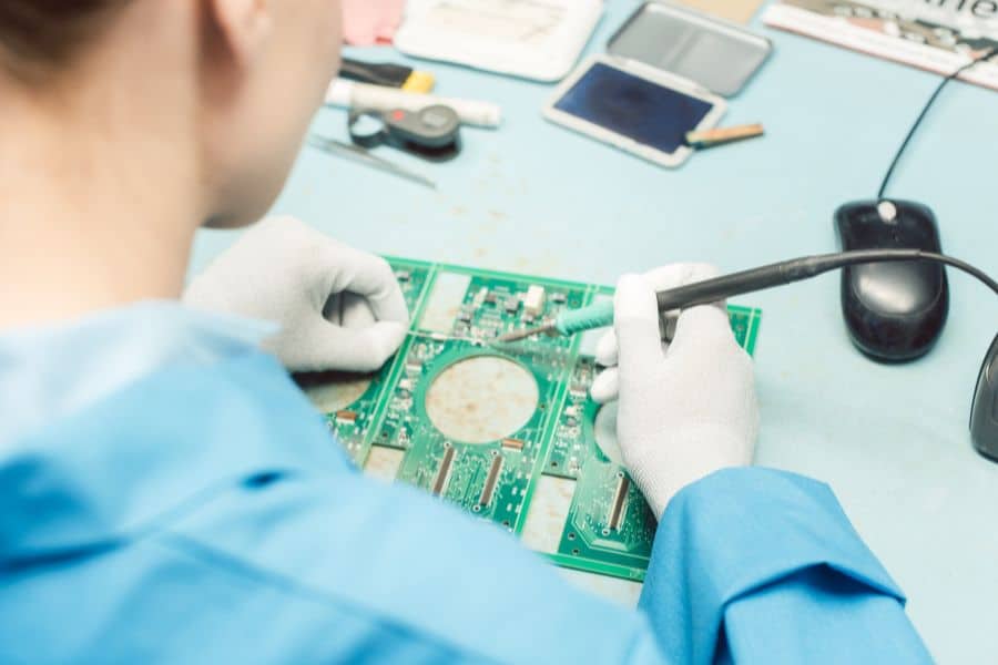 Technician hand soldering DIP components on a printed circuit board